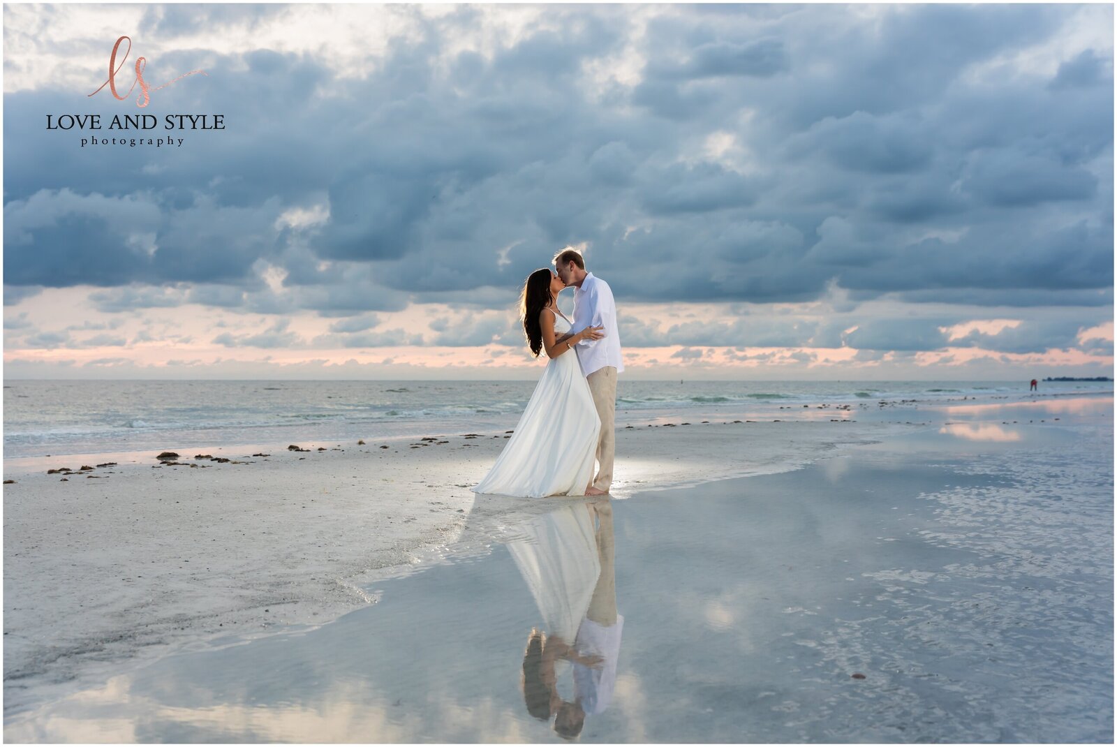 Engaged couple kissing against a  moody sky on Anna Maria Island