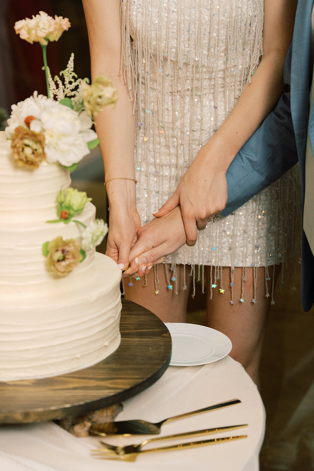Cake cutting in bride’s sparkly tassel reception dress.