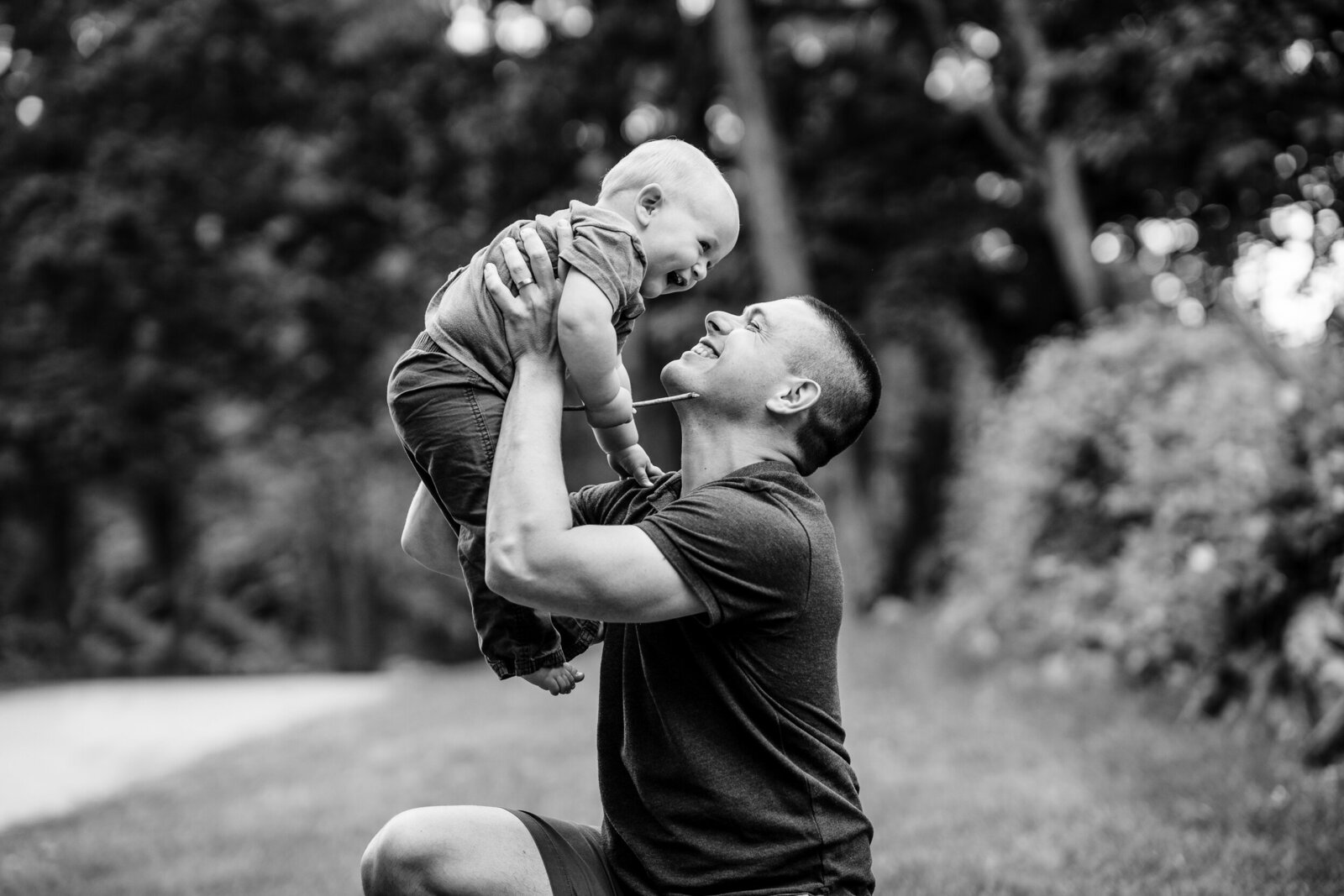 black and white portrait of father lifting son into air