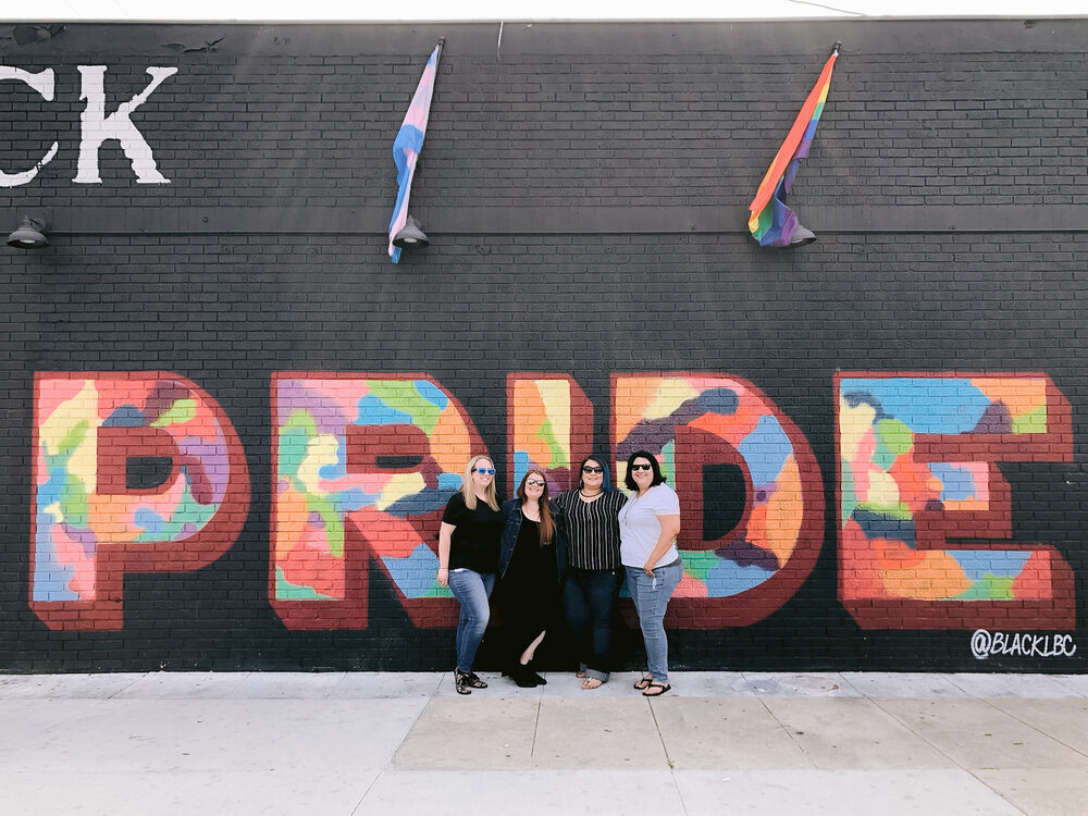 4 lesbians stand in front of Pride mural