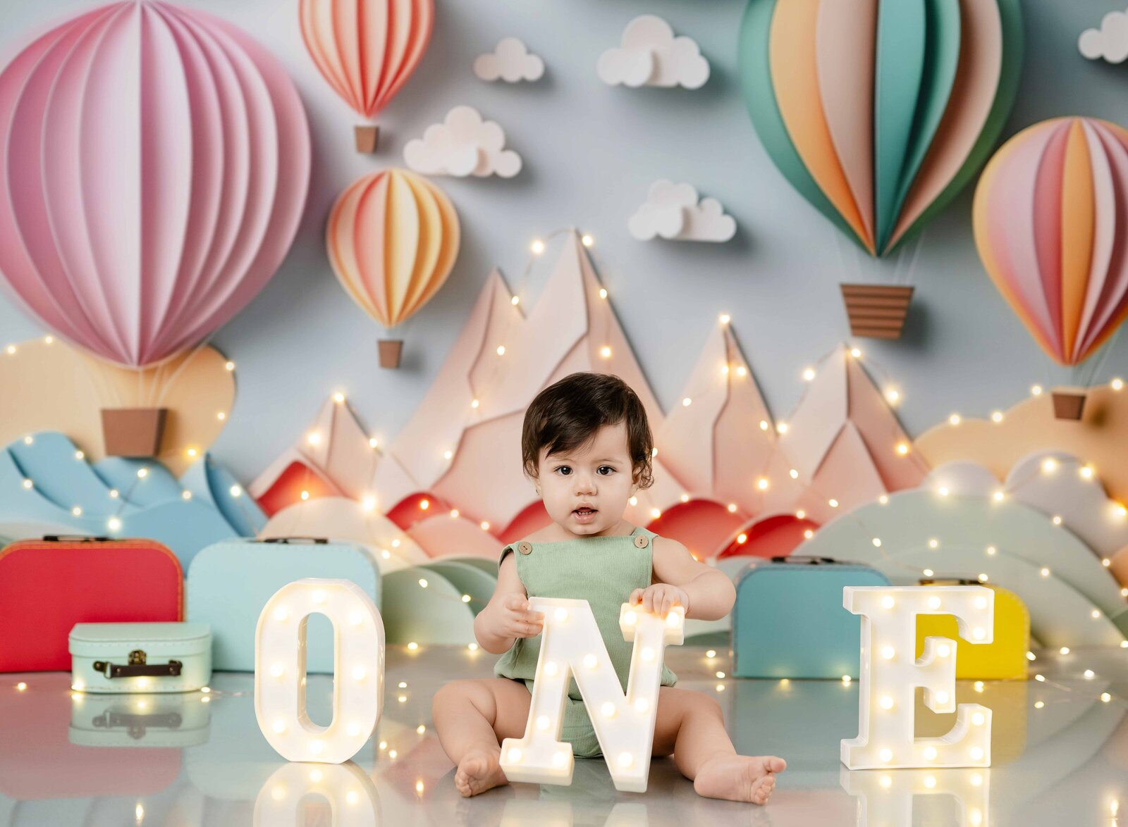 baby holding lighted ONE numbers for his birthday photo.