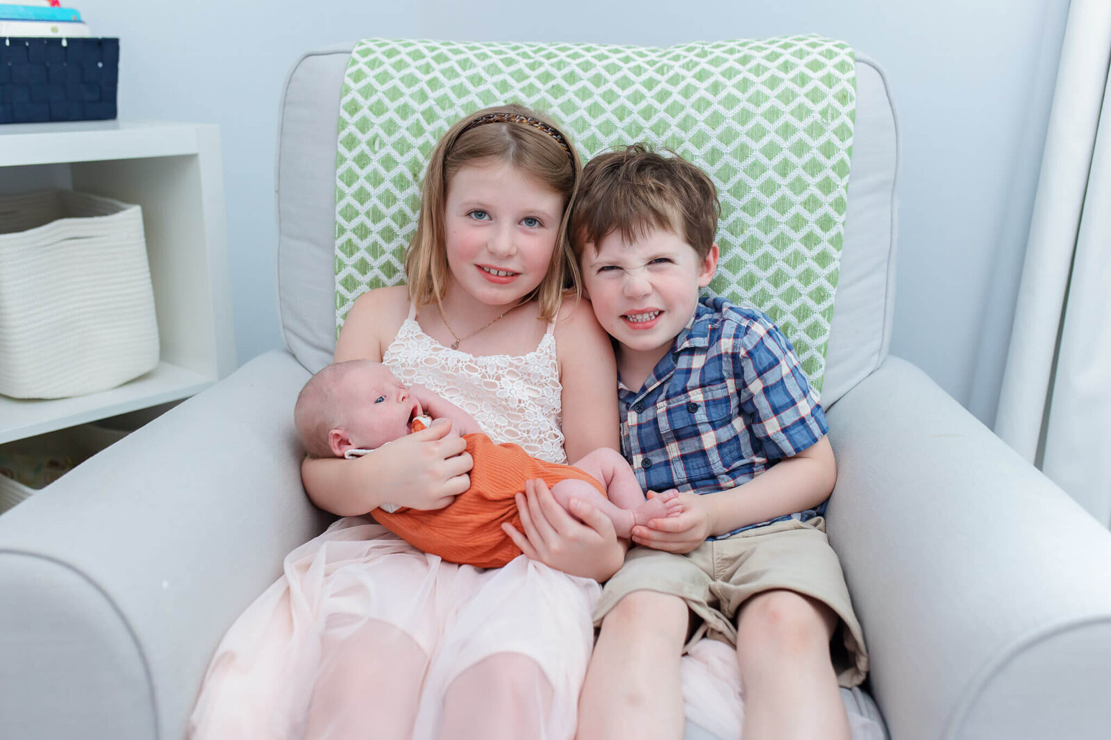 A big brother and sister holding their newborn brother.