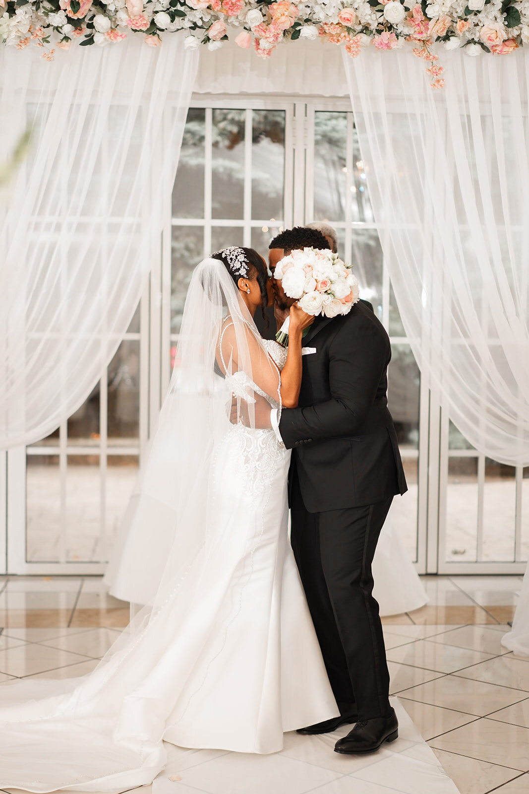 bride and groom kissing at ceremony with bouque