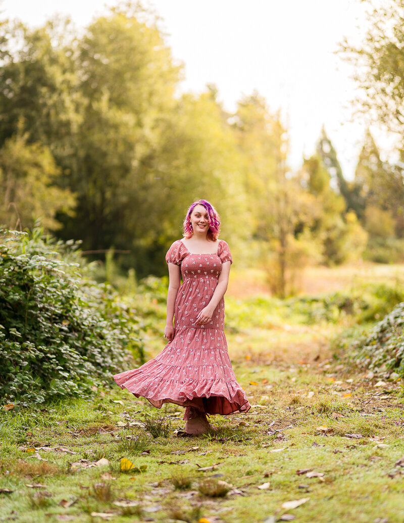 senior-portrait-in-lush-green-forest-girl-in-pink-dress-twirling