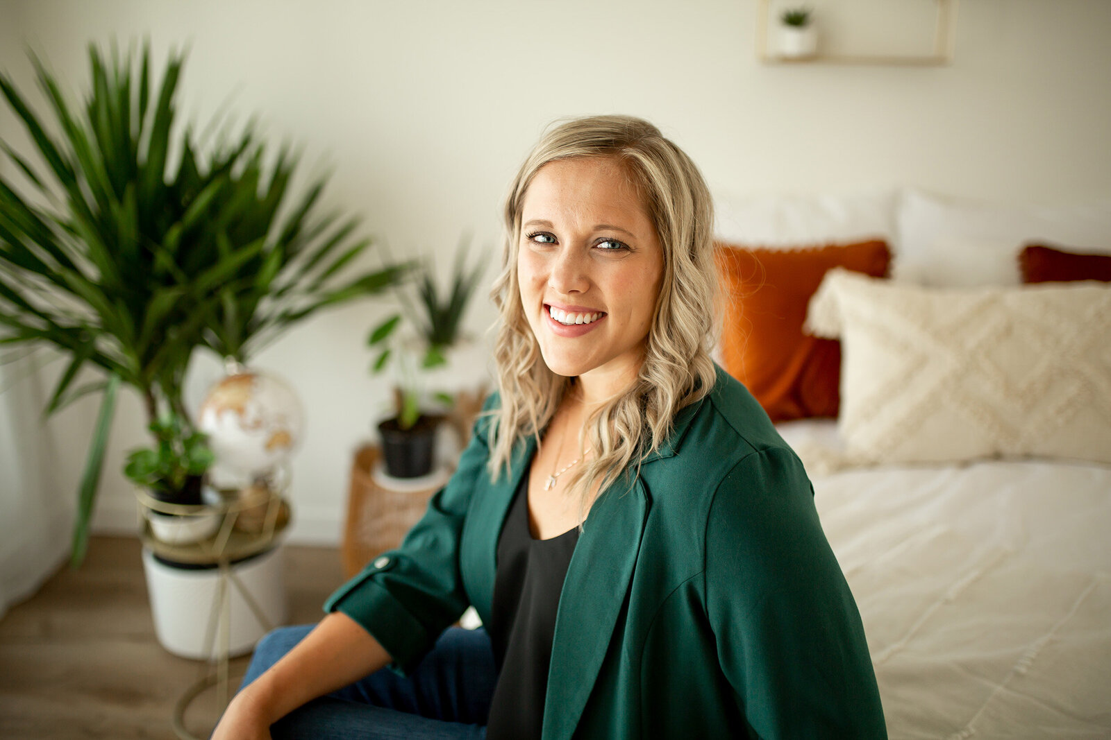 blonde woman sitting on bed smiling