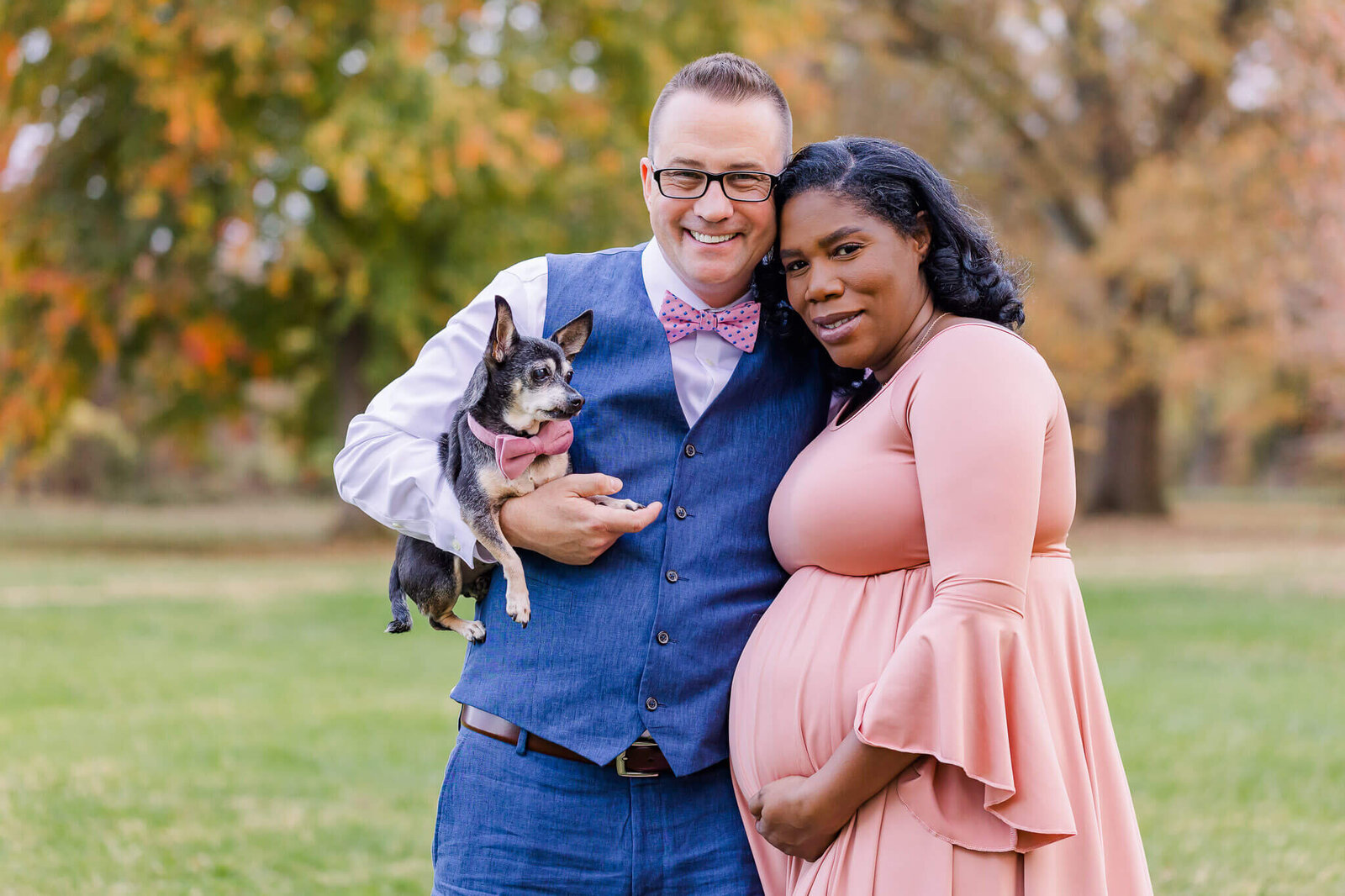 An expecting couple and their dog posing for their maternity portraits at Fort Hunt Park.