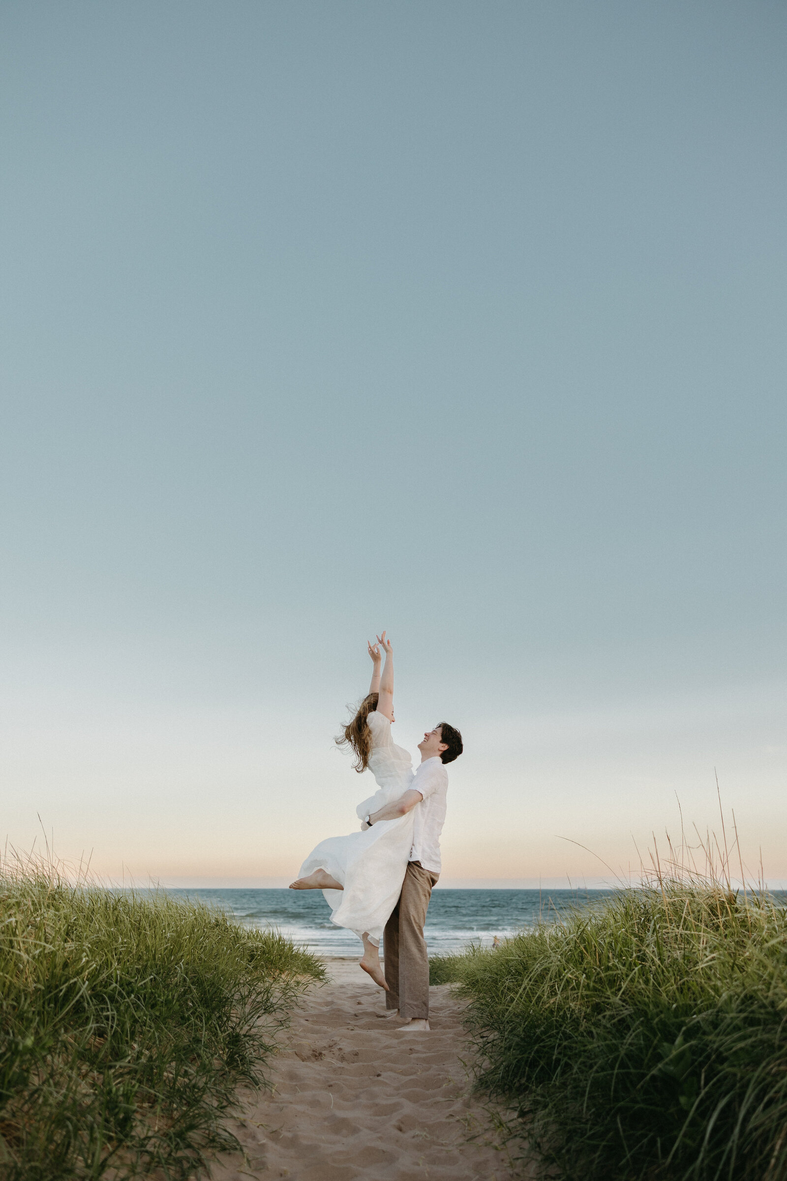 A man lifts his fiance into the air at their engagement session in Halifax, Nova Scotia. 