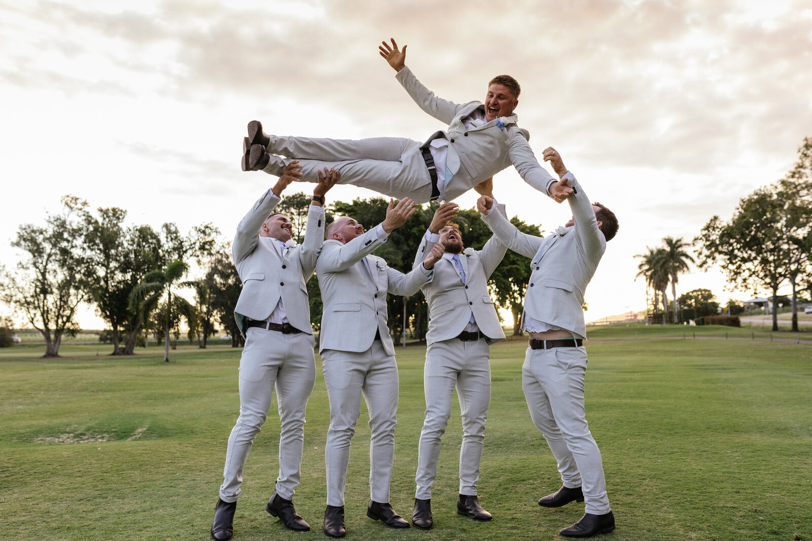 Groomsmen throwing the groom into the air on a golf course photographed by a Bendigo wedding photographer.