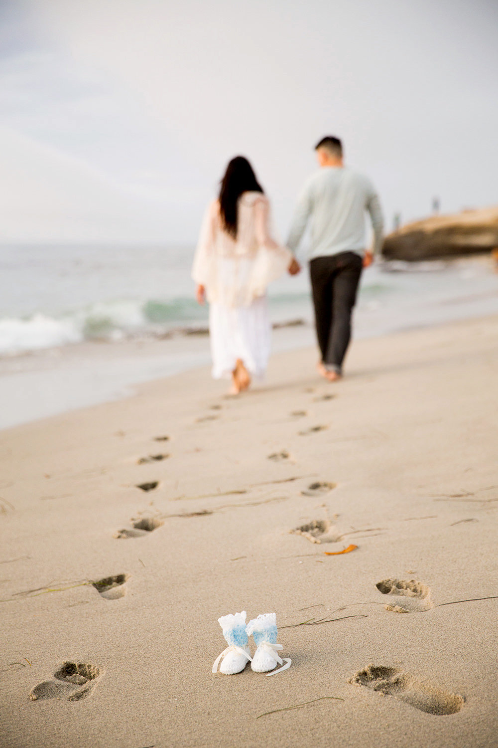 Fun Maternity photo with baby shoes at the beach in La Jolla.