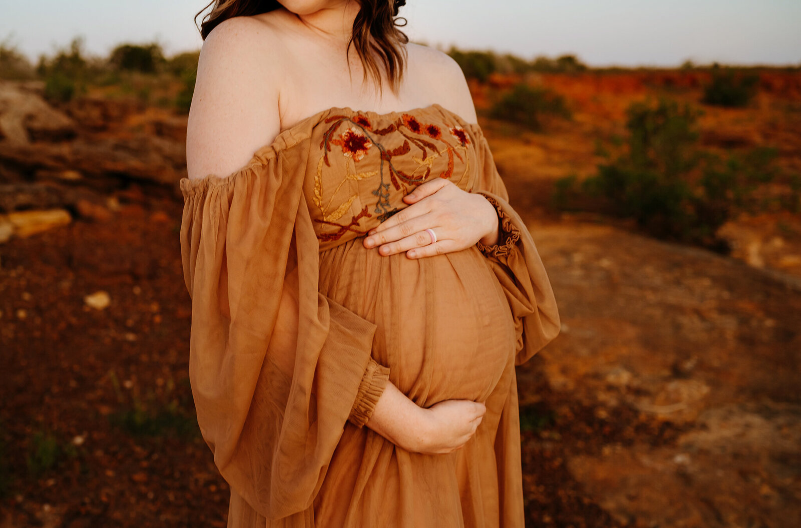 Glowing mother-to-be cradling baby bump during golden hour maternity session in Fort Worth by Paula Goforth Photography.