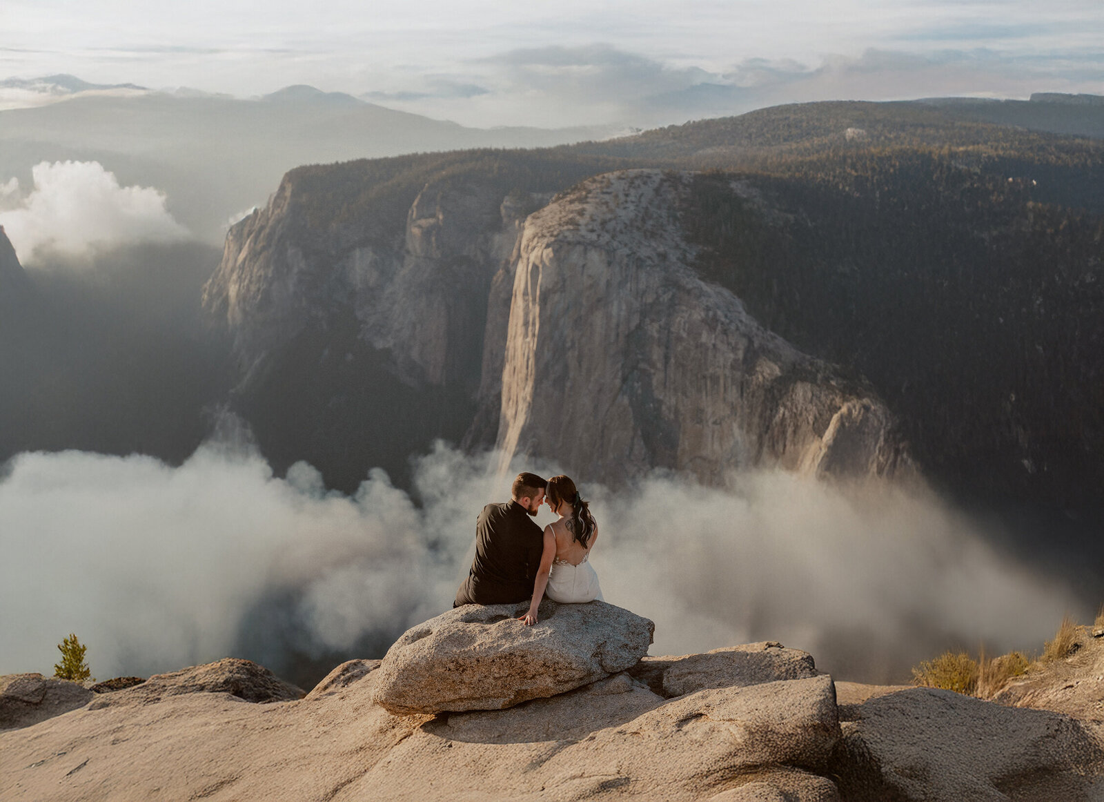 photograph of a bride and groom enjoying the views of their destination elopement in yosemite with el capitan and smoke billowing in the background