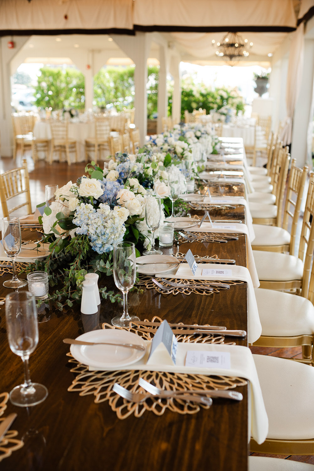 long table top settings with fancy chargers and neutral florals