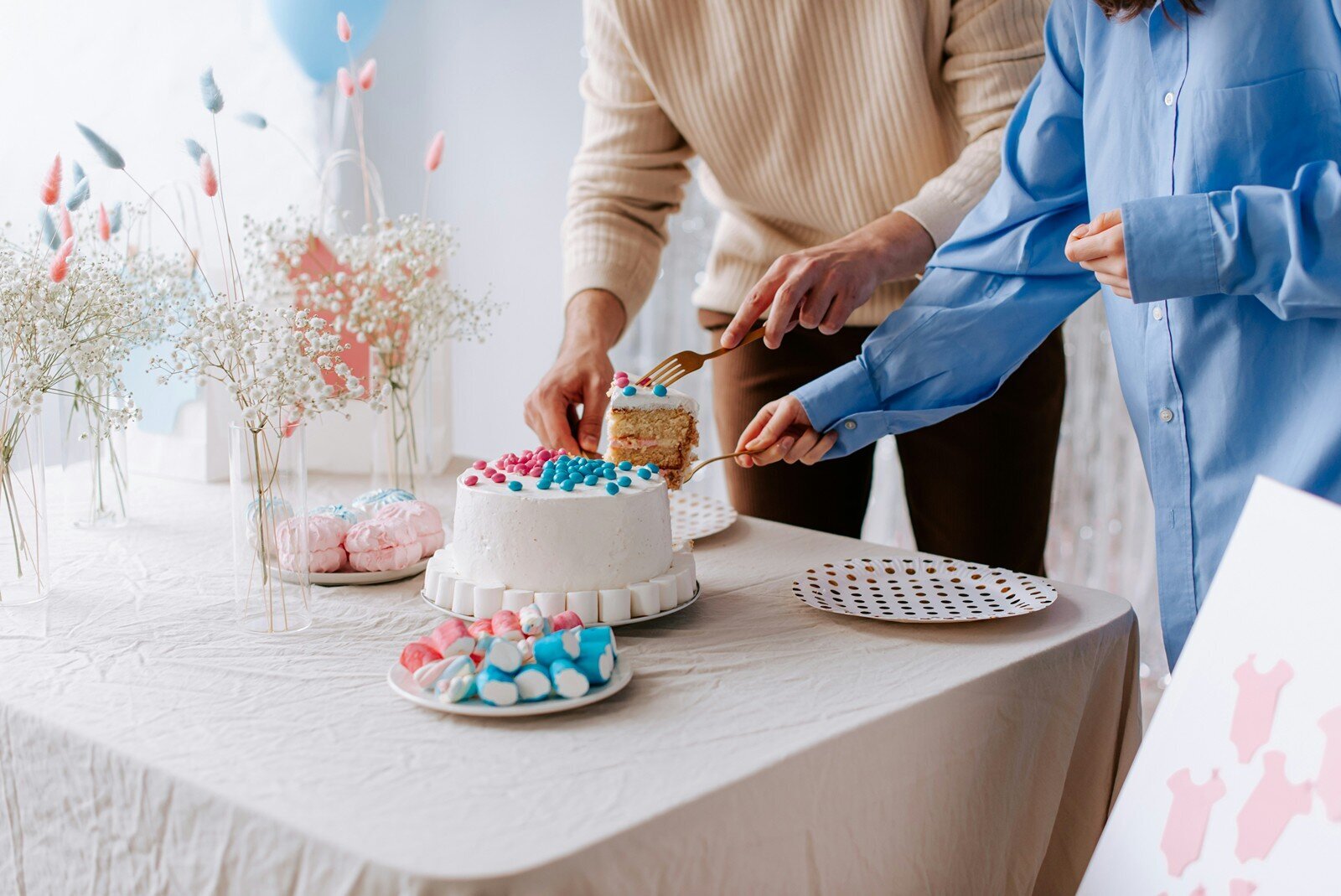 Couple cutting a gender reveal cake with pink and blue details