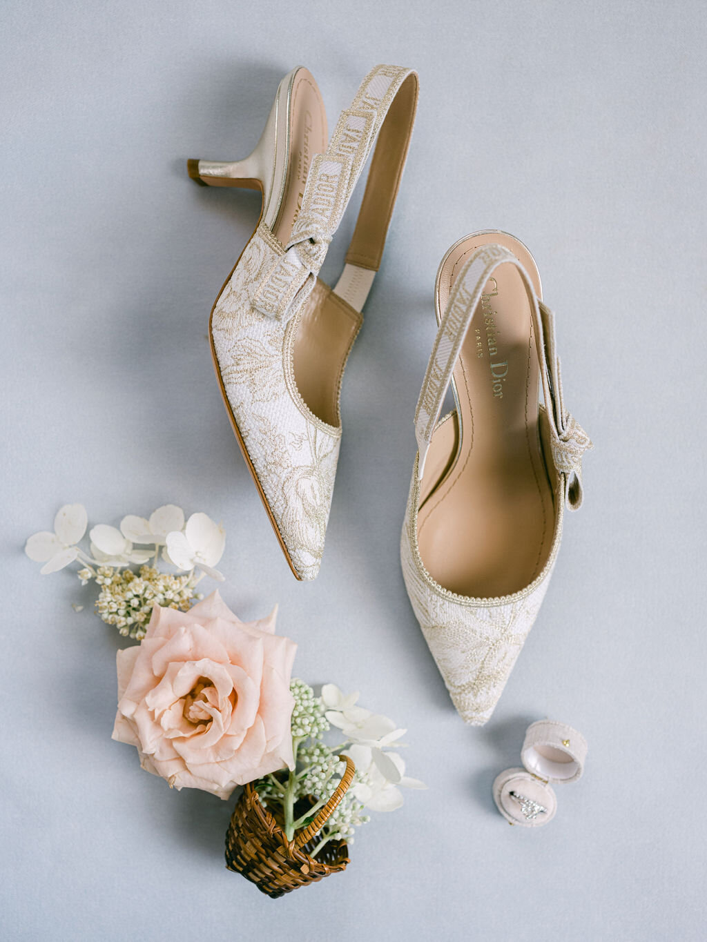 Flatlay of bride’s shoes and ring with peach rose and white hydrangea.