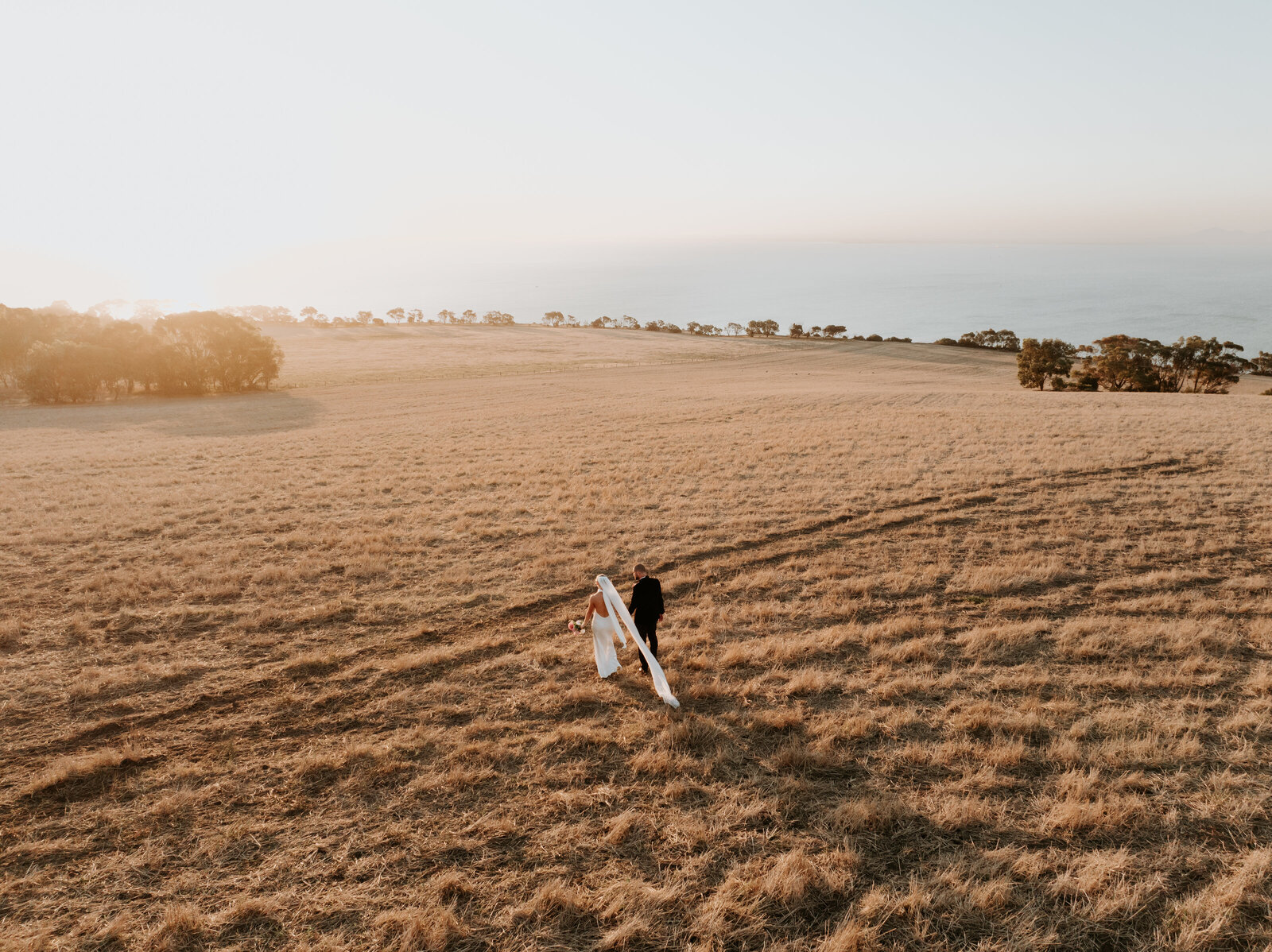 Bride and groom walking towards sunset