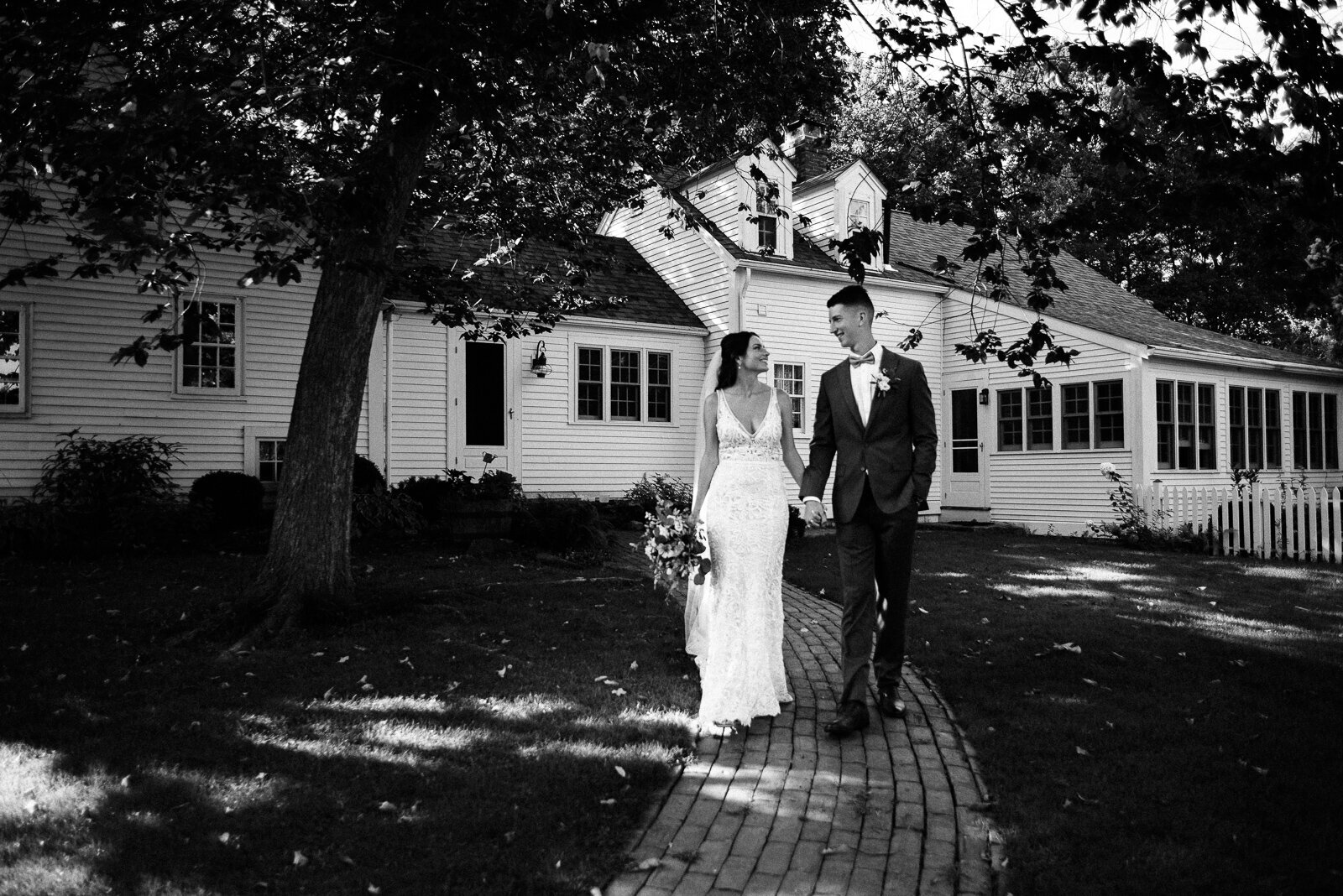 Black and white photo of bride and groom walking along a path