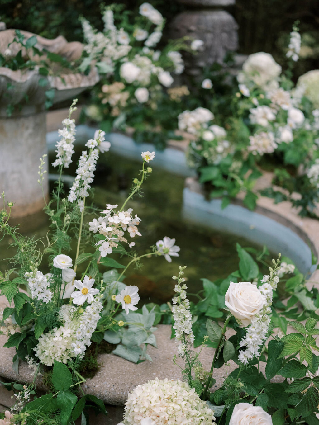 Florals covering water fountain at the Evergreen Museum ceremony include white larkspur, white quick-fire hydrangea, white Japanese anemone, white lisianthus, white garden roses and lush organic greenery.