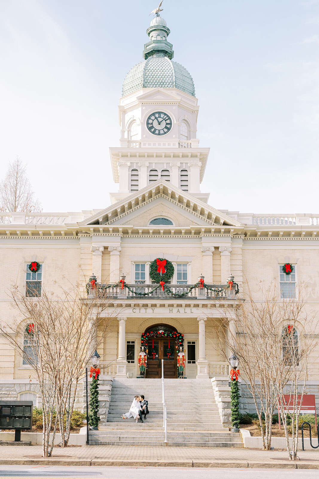 couple sits on the steps of the city hall in athens georgia