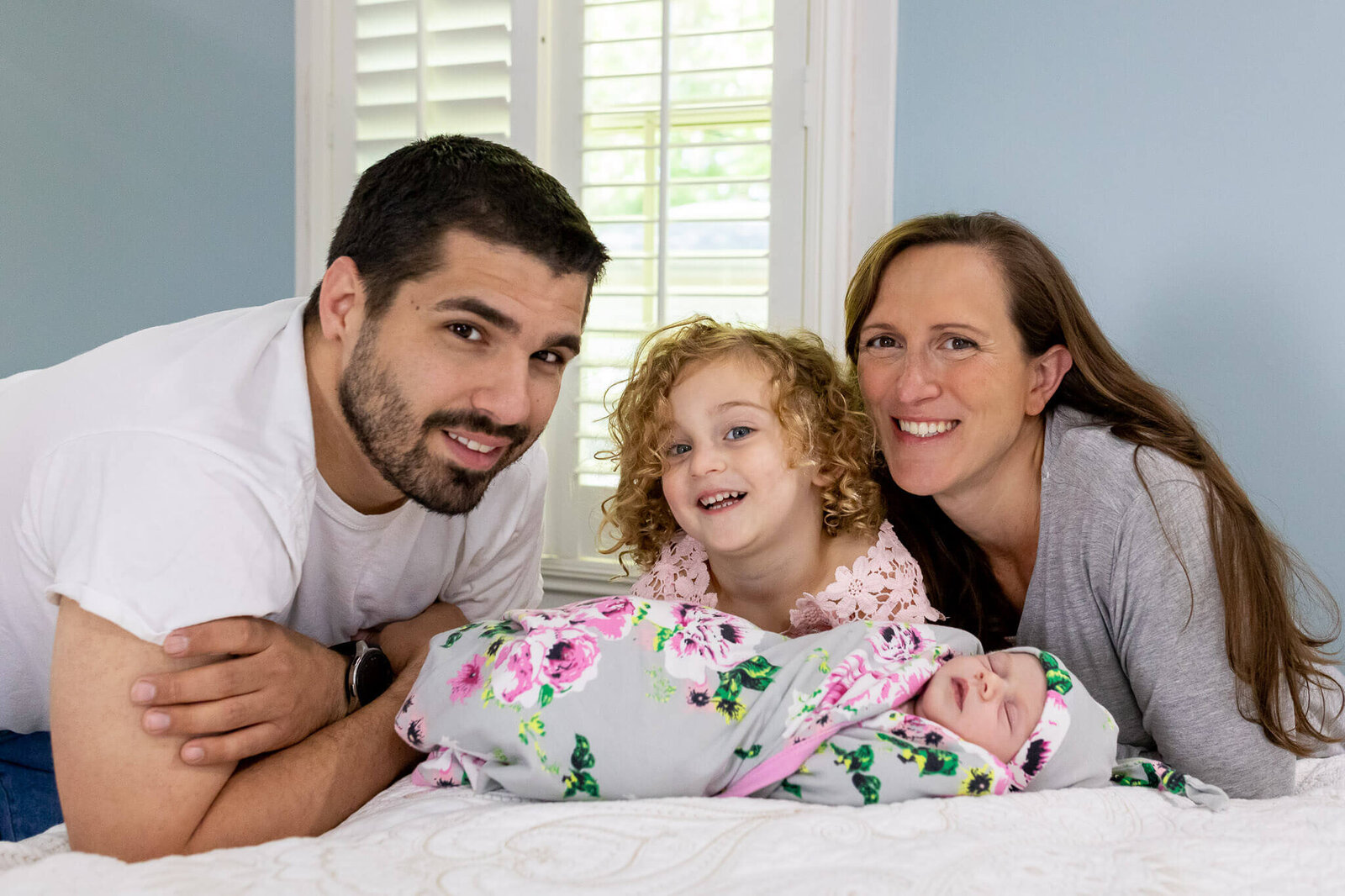 A family of four smiling for the camera during Alexandria newborn photos.