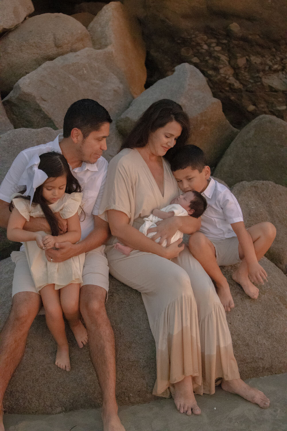Family sitting on rocks, mother cradling a newborn