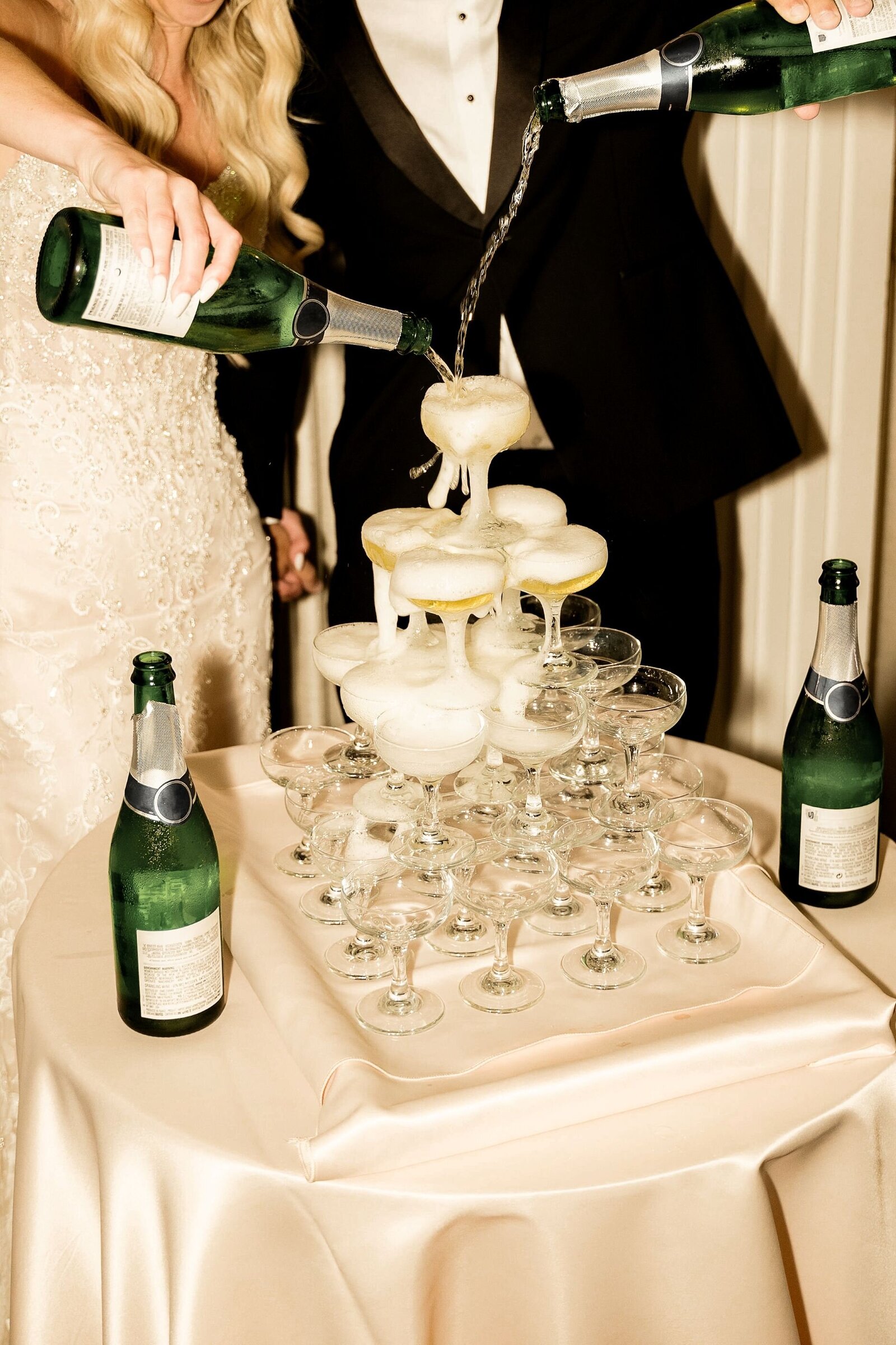 Wedding champagne tower being filled by bride