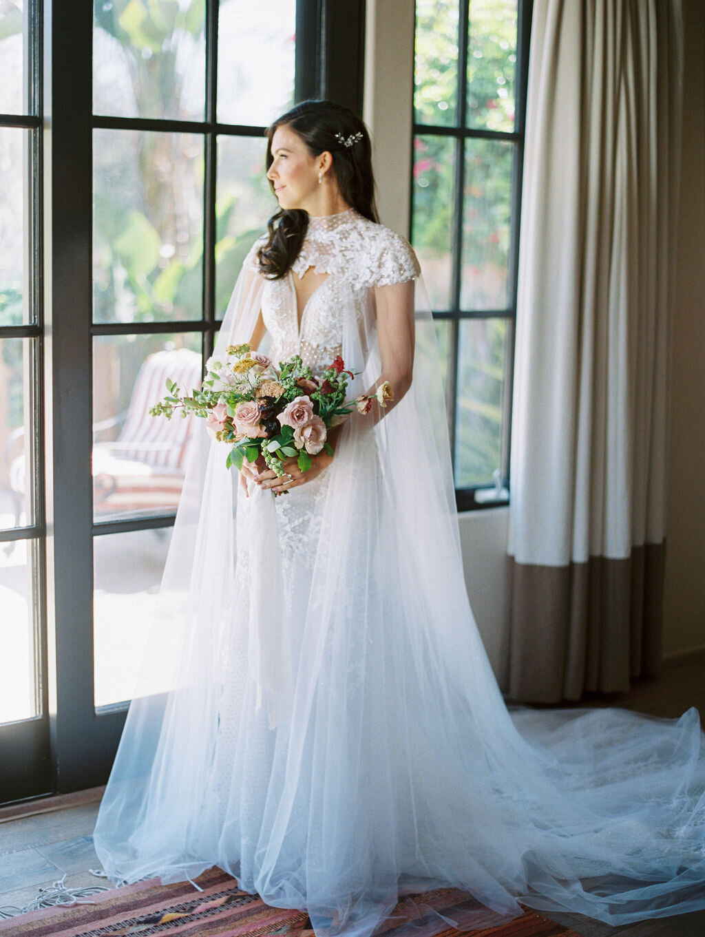 Bride wearing lace gown by Berta with a tulle cape
