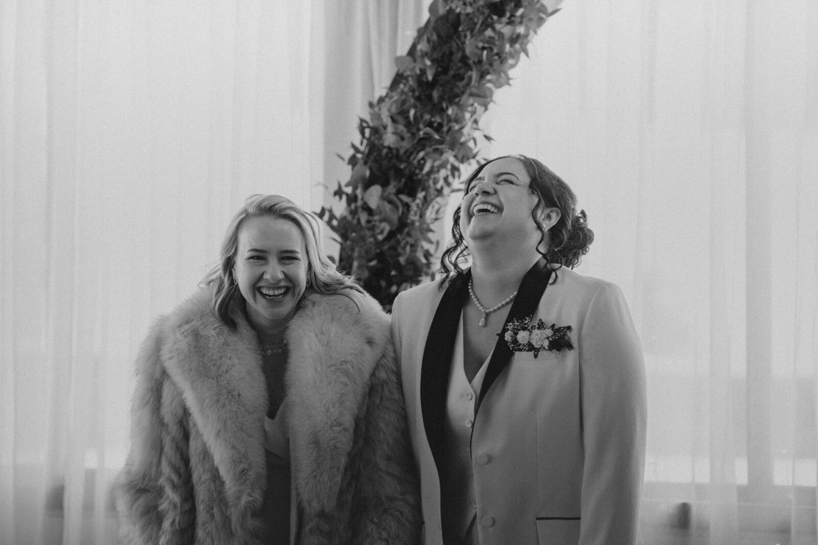 Two wives laugh at the altar of their wedding ceremony
