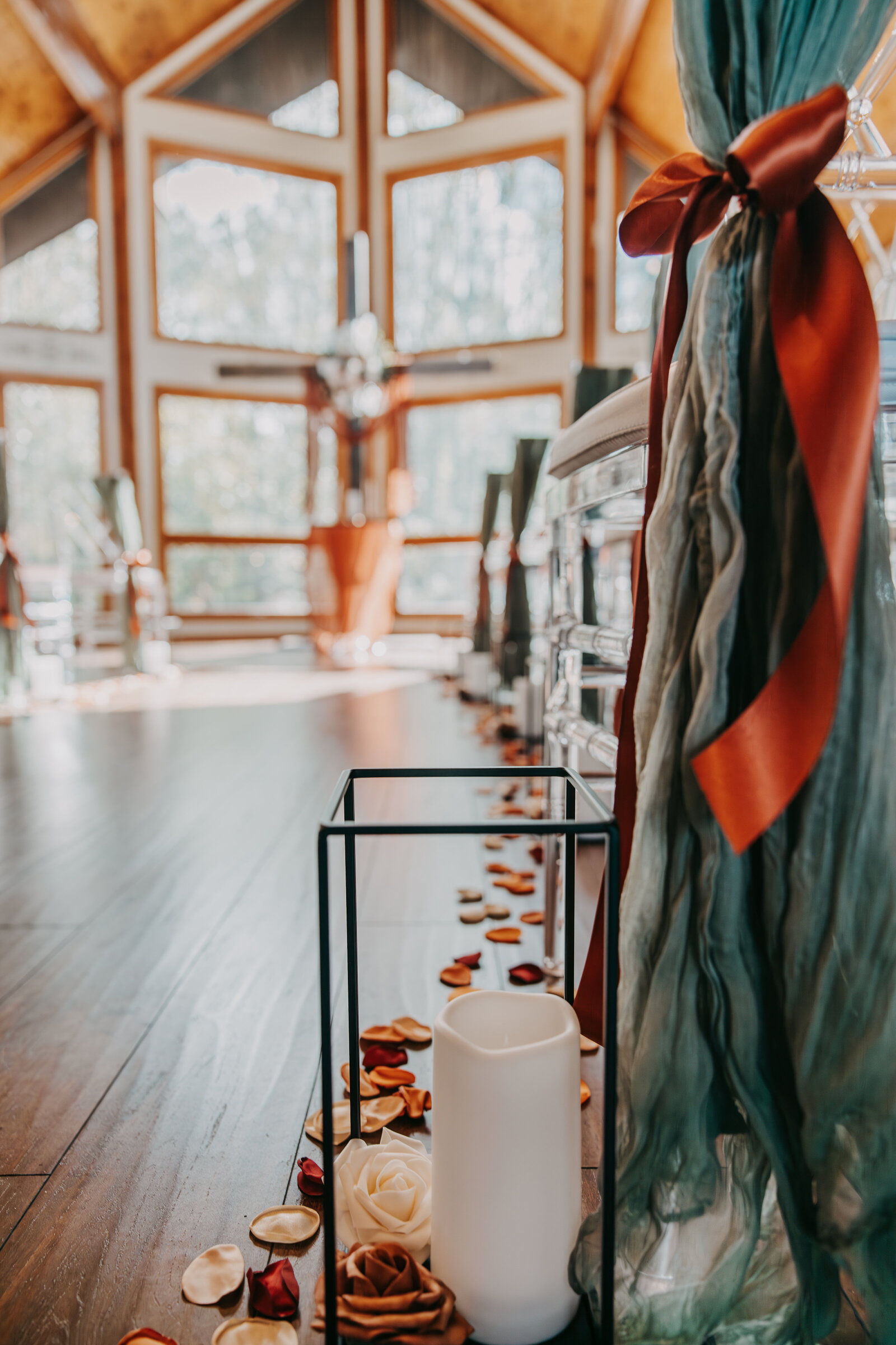 Kincaid Manor ceremony room with aisle setup, candles in metal frames, and fall-colored petals lining the floor for a romantic atmosphere.