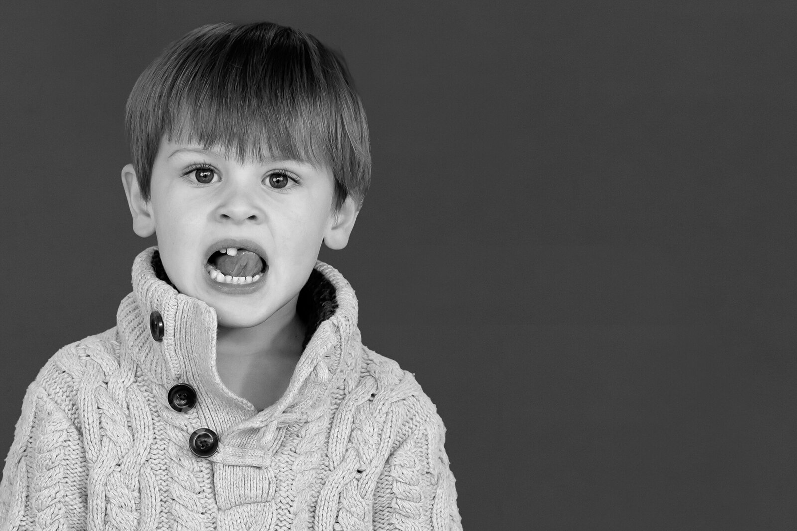 Preschool boy playing with a loose tooth with his tounge, black and white image, for his school photo