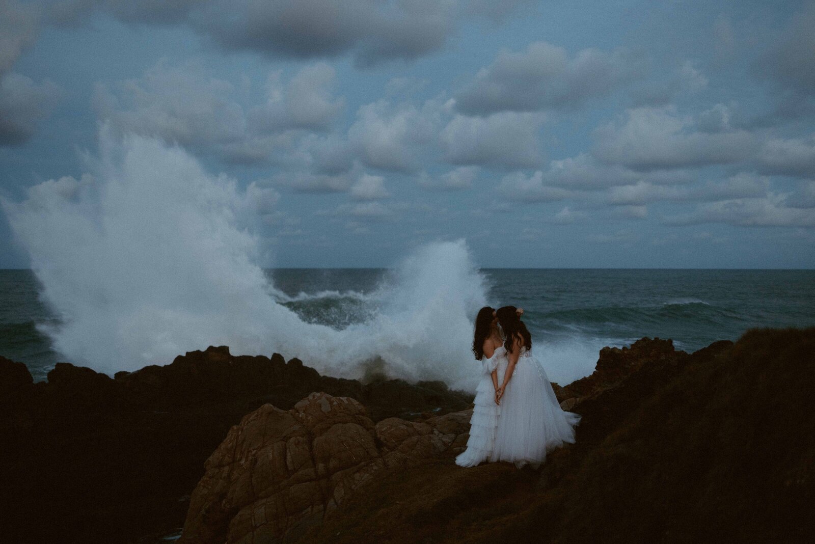 two brides on top of a cliff overlooking the rugged ocean byron bay australia  lgbtq+ally  friendly