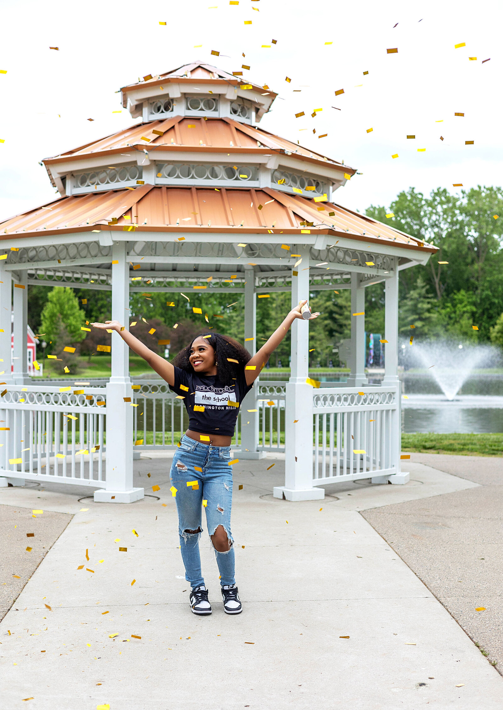 Senior girl standing in front of gazebo celebrating in confetti