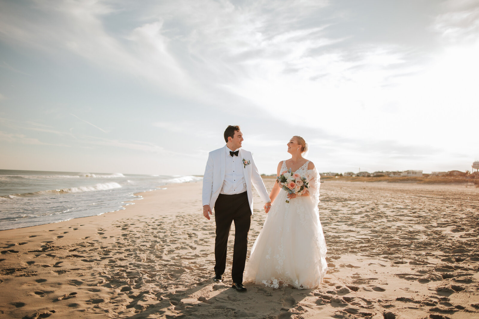 Bride and groom on wedding day. Standing together, holding hands, and walking while at the beach in Long Beach Island.