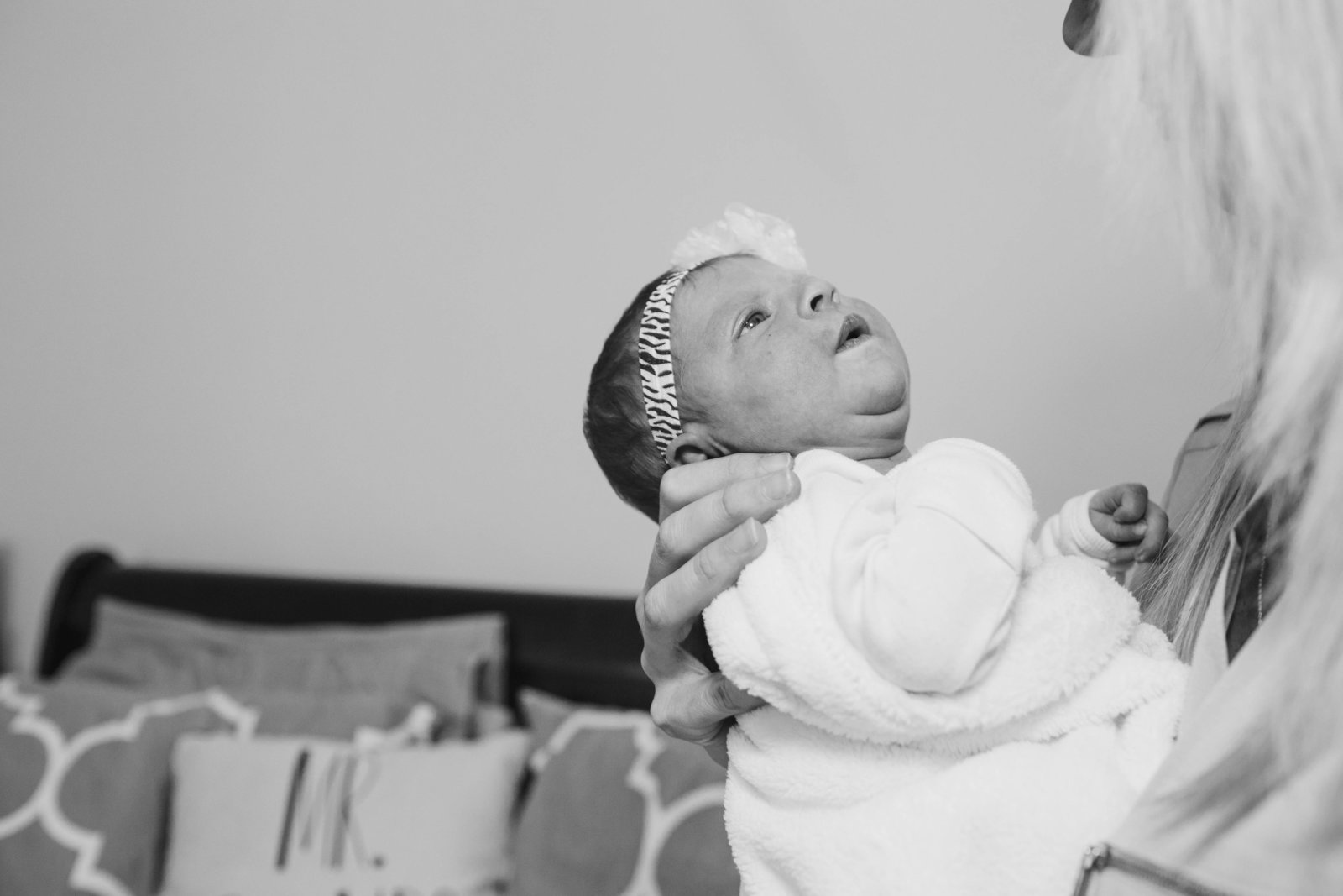 mom holds her newborn baby girl in her arms during an in-home newborn lifestyle session
