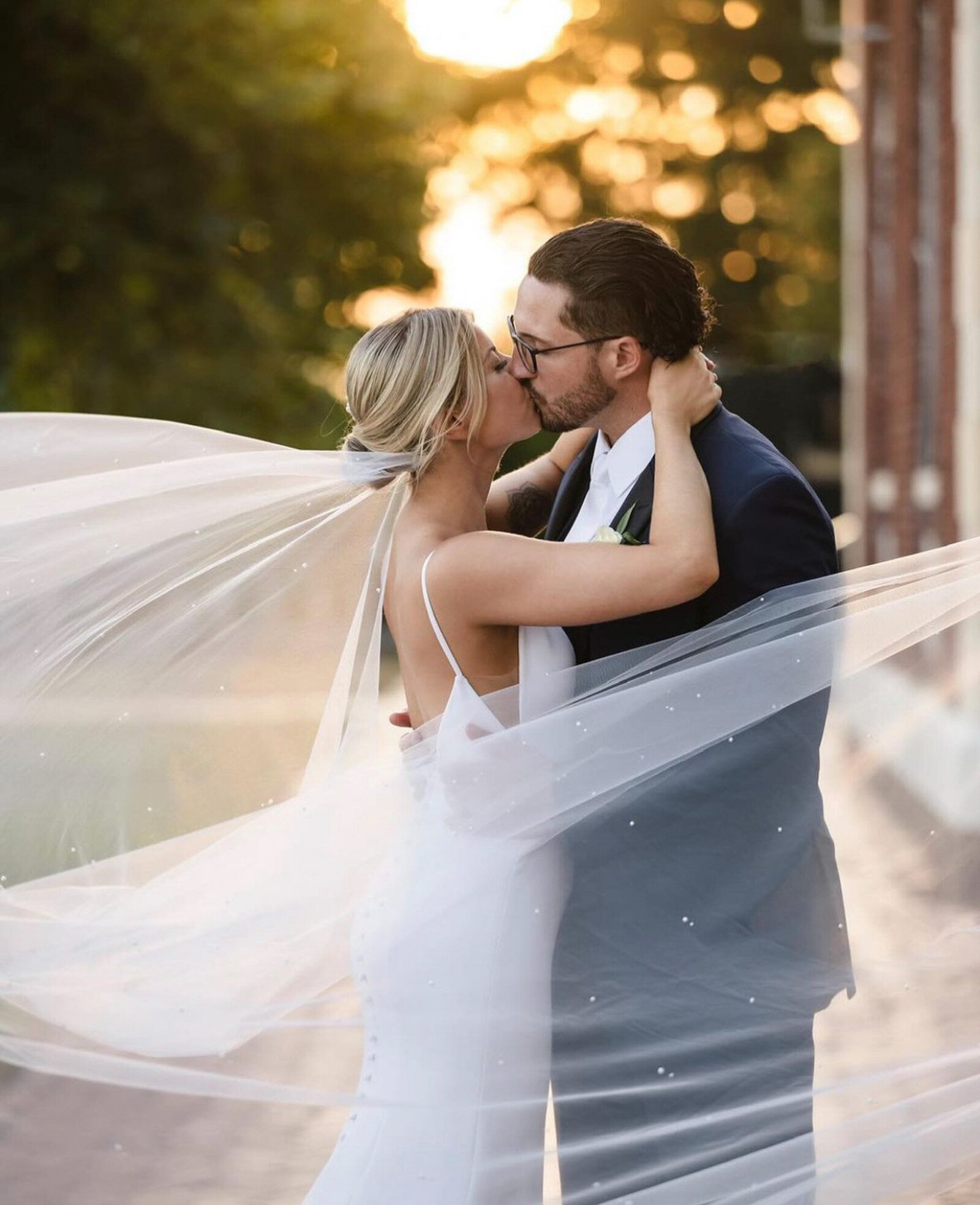 newlywed couple share a kiss outdoors at sunset