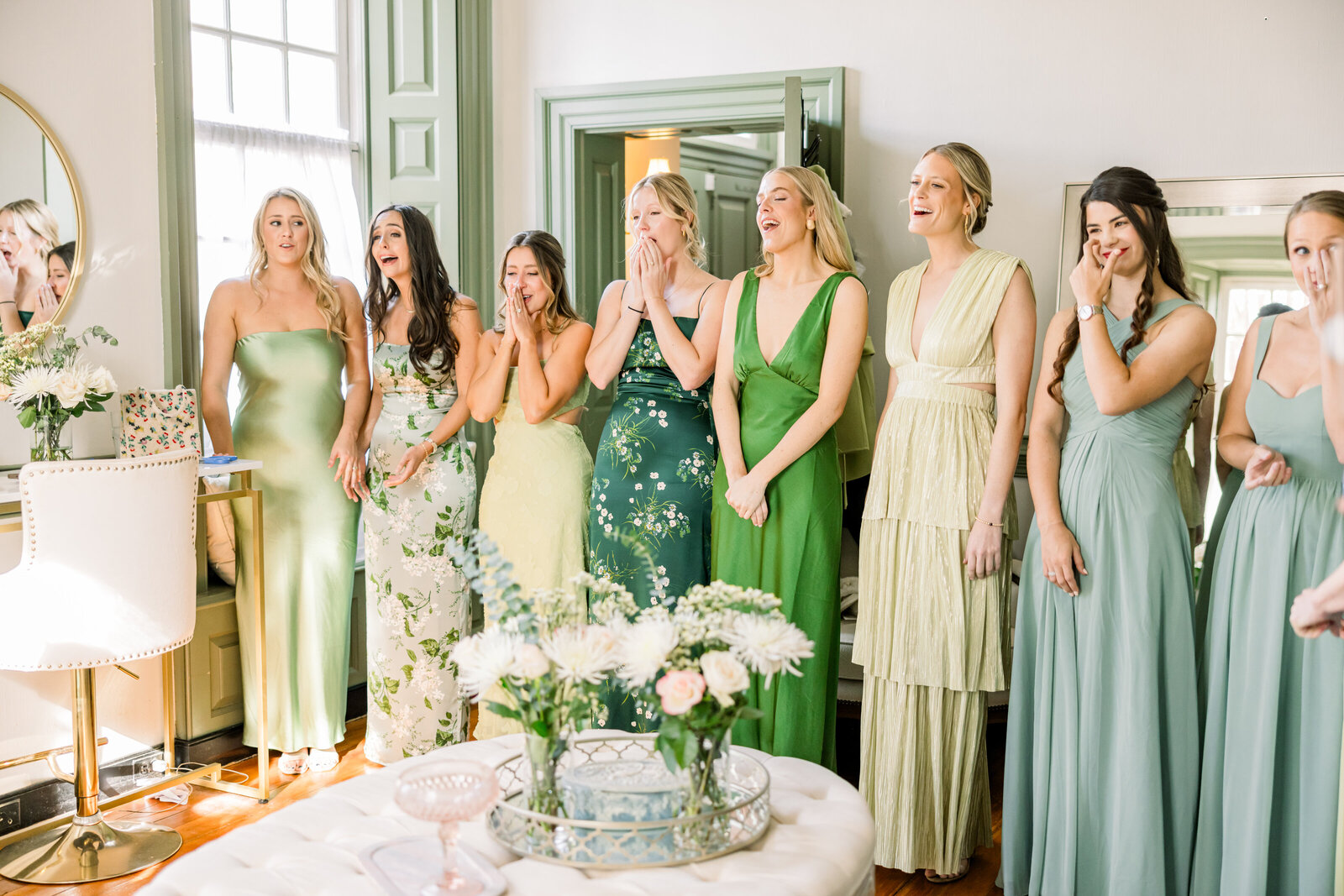 Bride’s emotional first look with bridesmaids dressed in beautiful floral prints with green tones, capturing a heartfelt and joyful wedding moment.