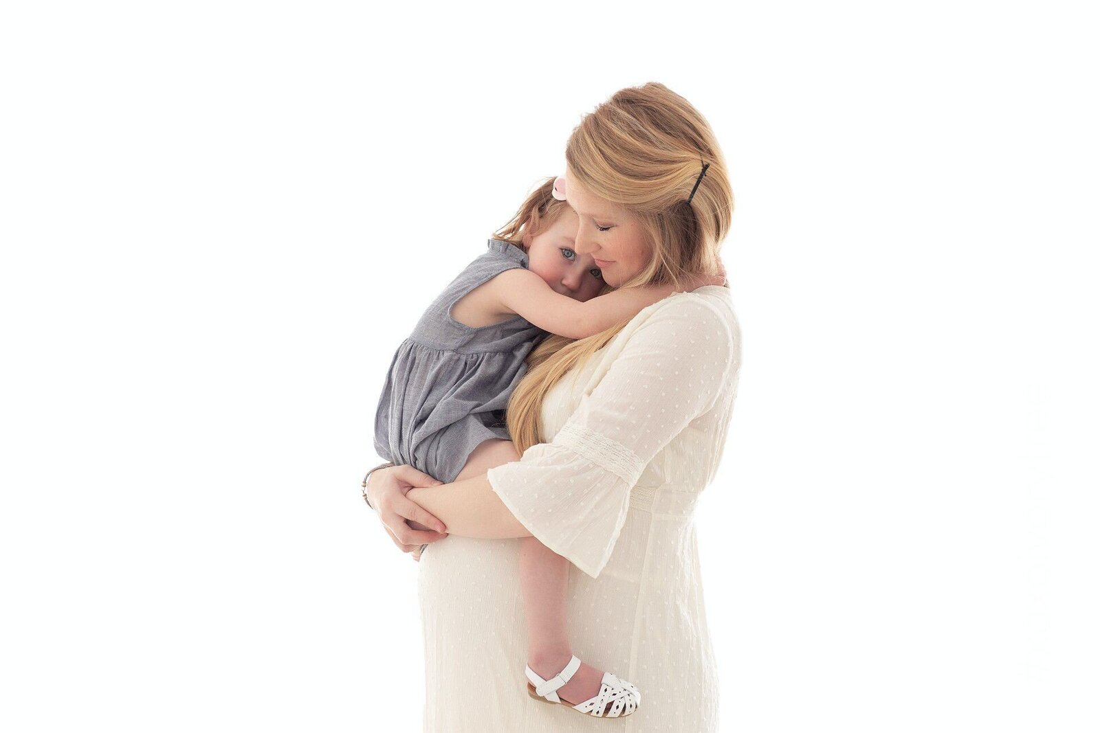 Elegant maternity portrait of a woman in a white bodycon dress standing in soft natural light, captured by Philadelphia maternity photographers.