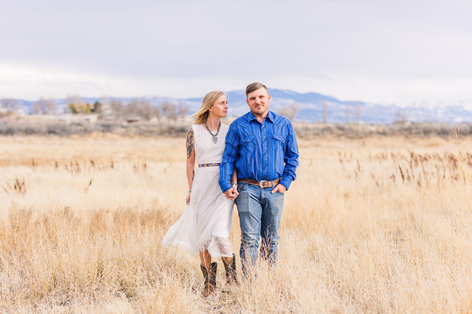 holding hands walking through a hayfield