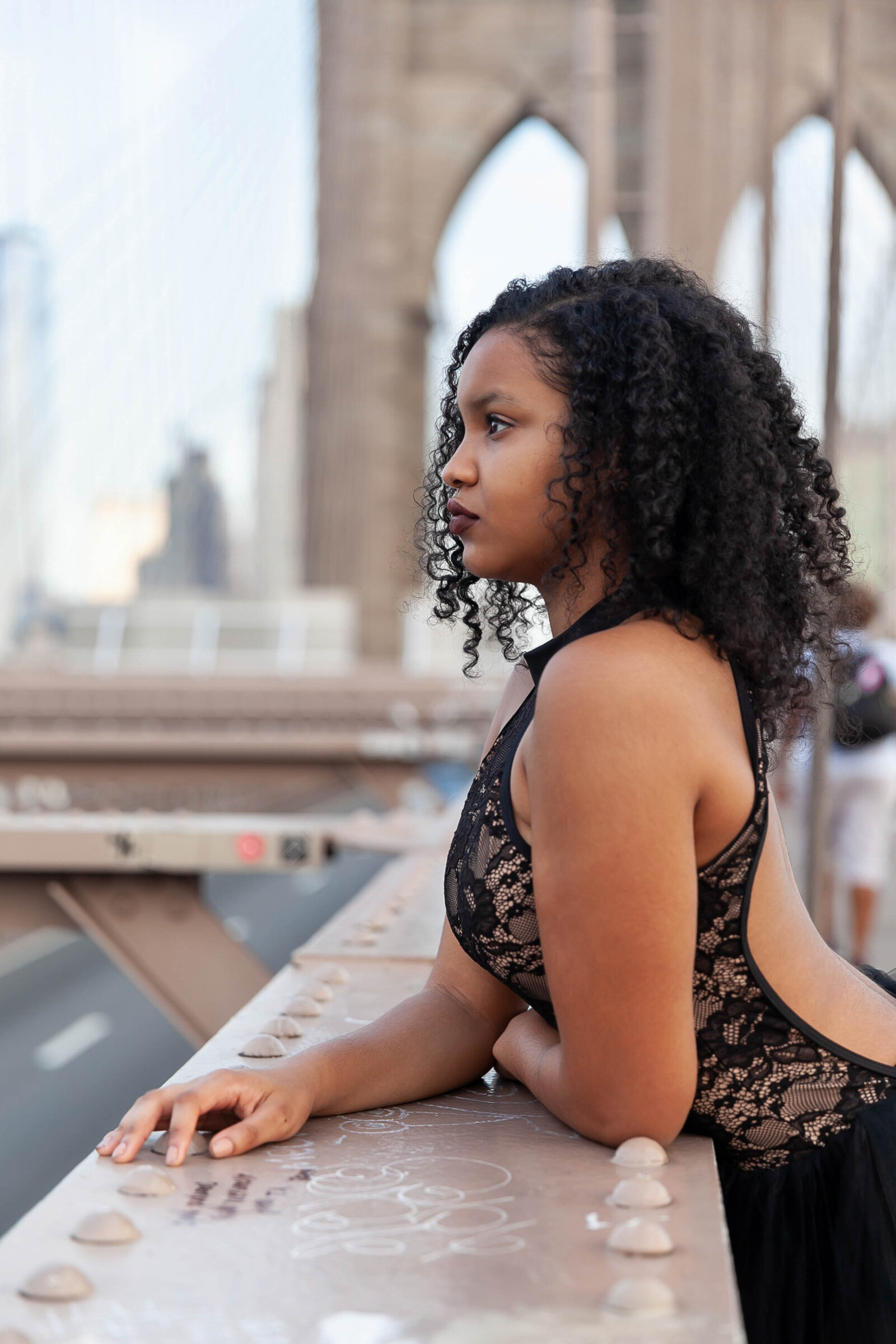 Profile of curly haired black woman dancer in lace leotard on Brooklyn Bridge