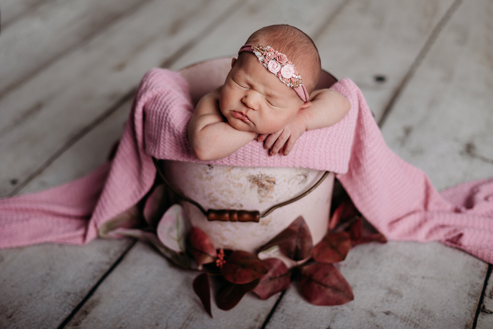 Newborn girl sleeping in bucket wrapped in pink