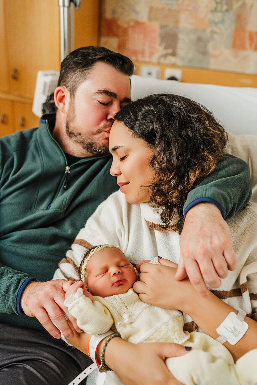 mom and dad snuggle on boston hospital bed during fresh 48 photoshoot