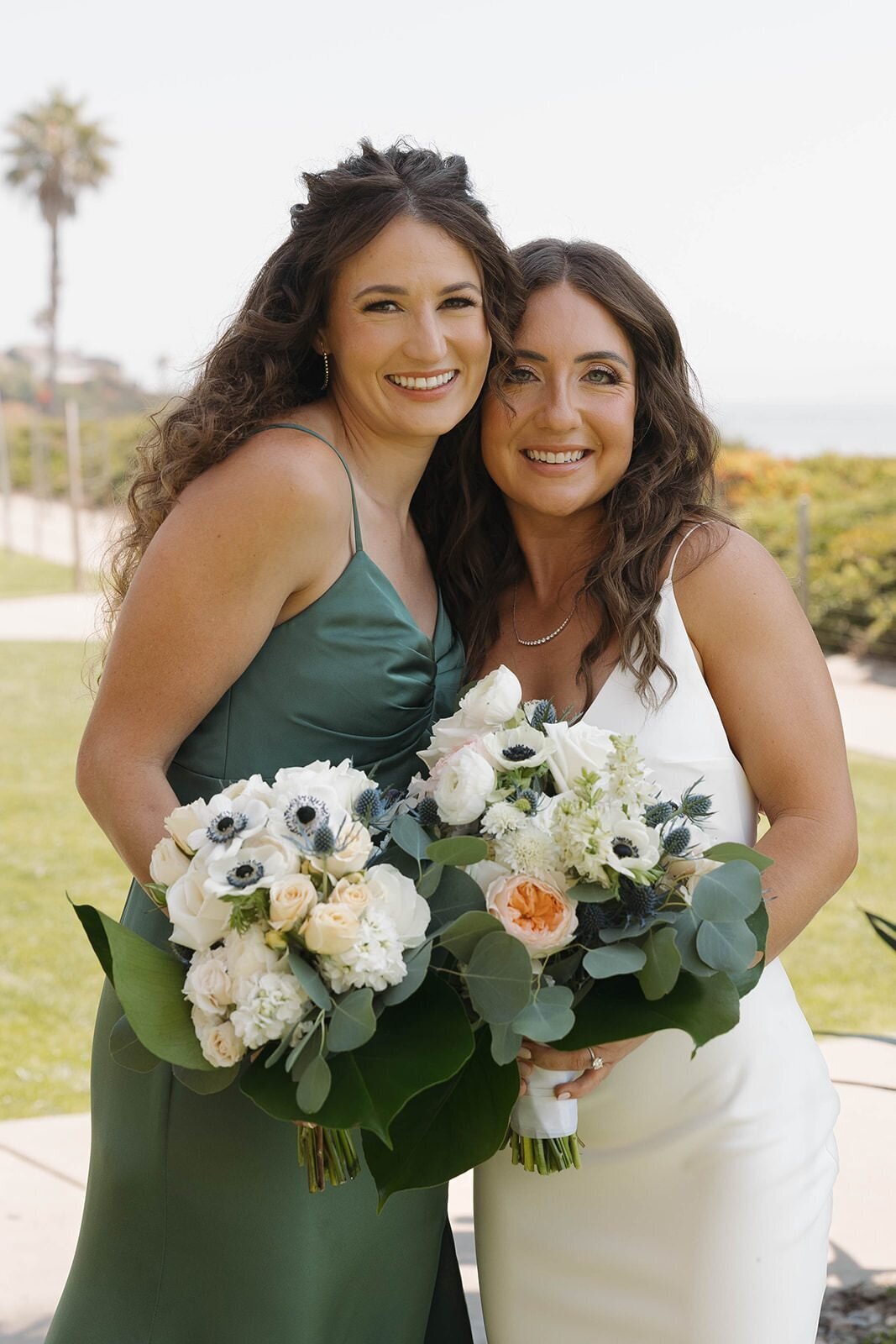 Bride and her bridesmaid in sage green holding bouquets