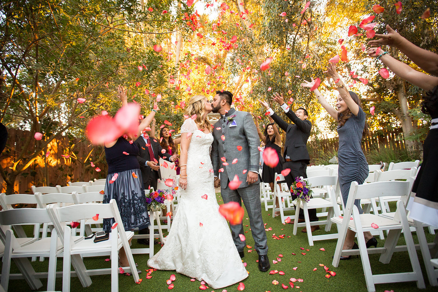 Amazing photo of the bride and groom showered in rose petals after their wedding ceremony