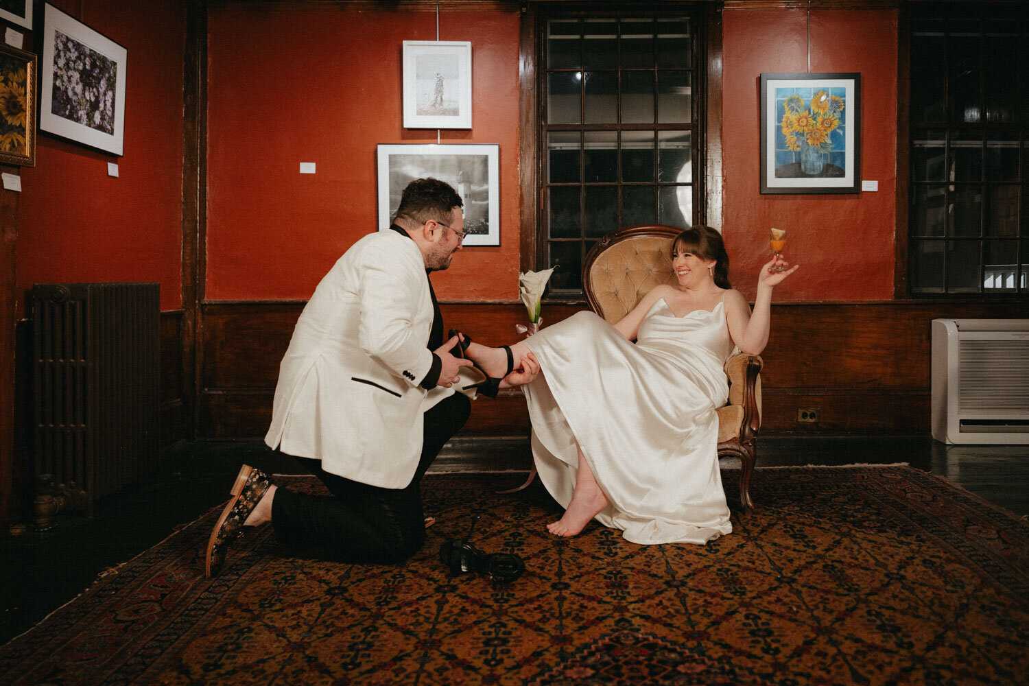 Groom helping her bride wear her wedding shoes