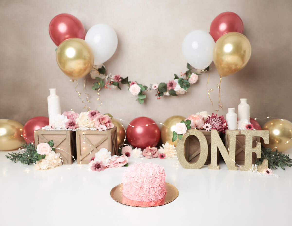 Girly cake smash with flowers, burgandy and gold balloons in our Rochester, NY studio.