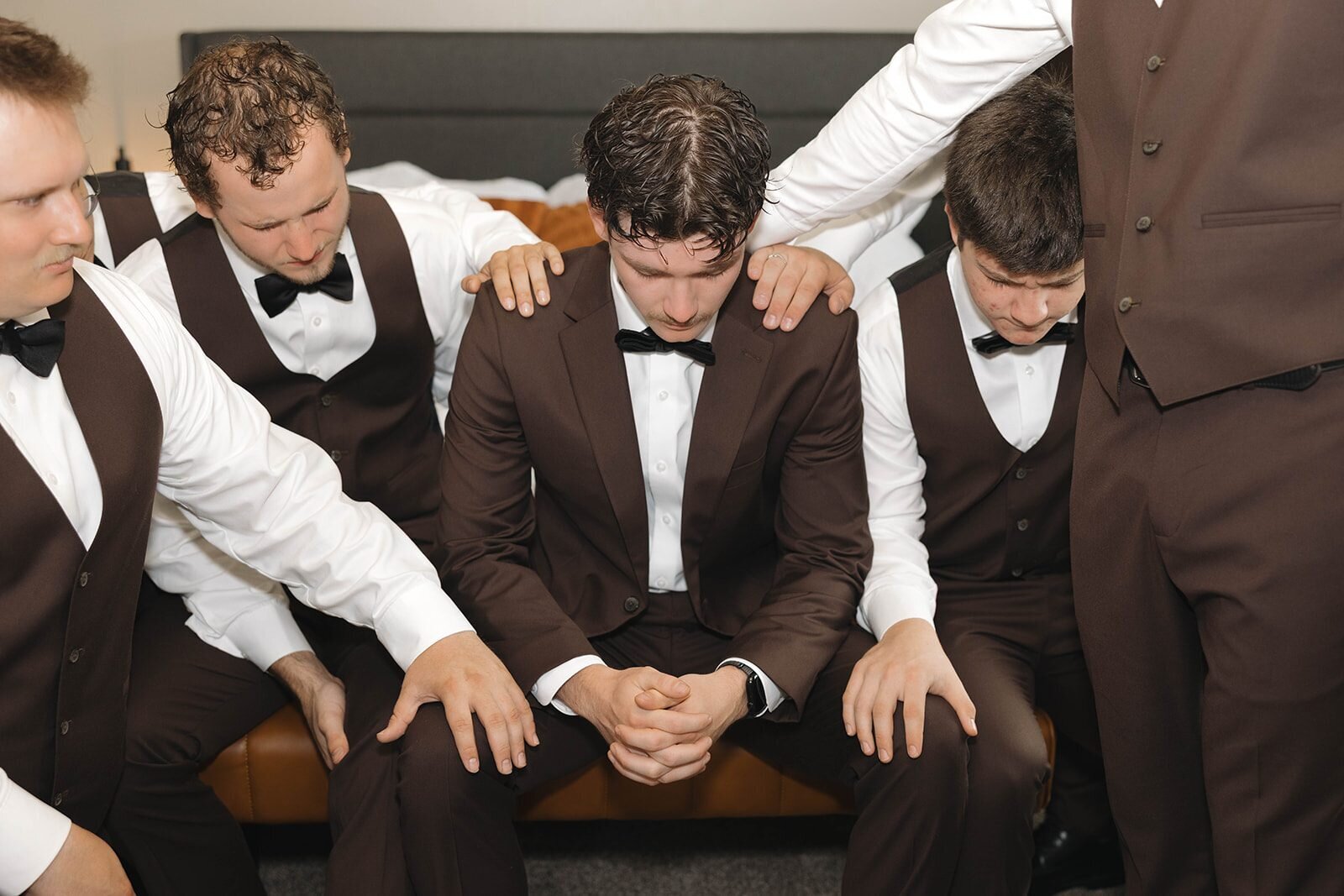 Groomsmen laying hands on the groom and praying before the ceremony