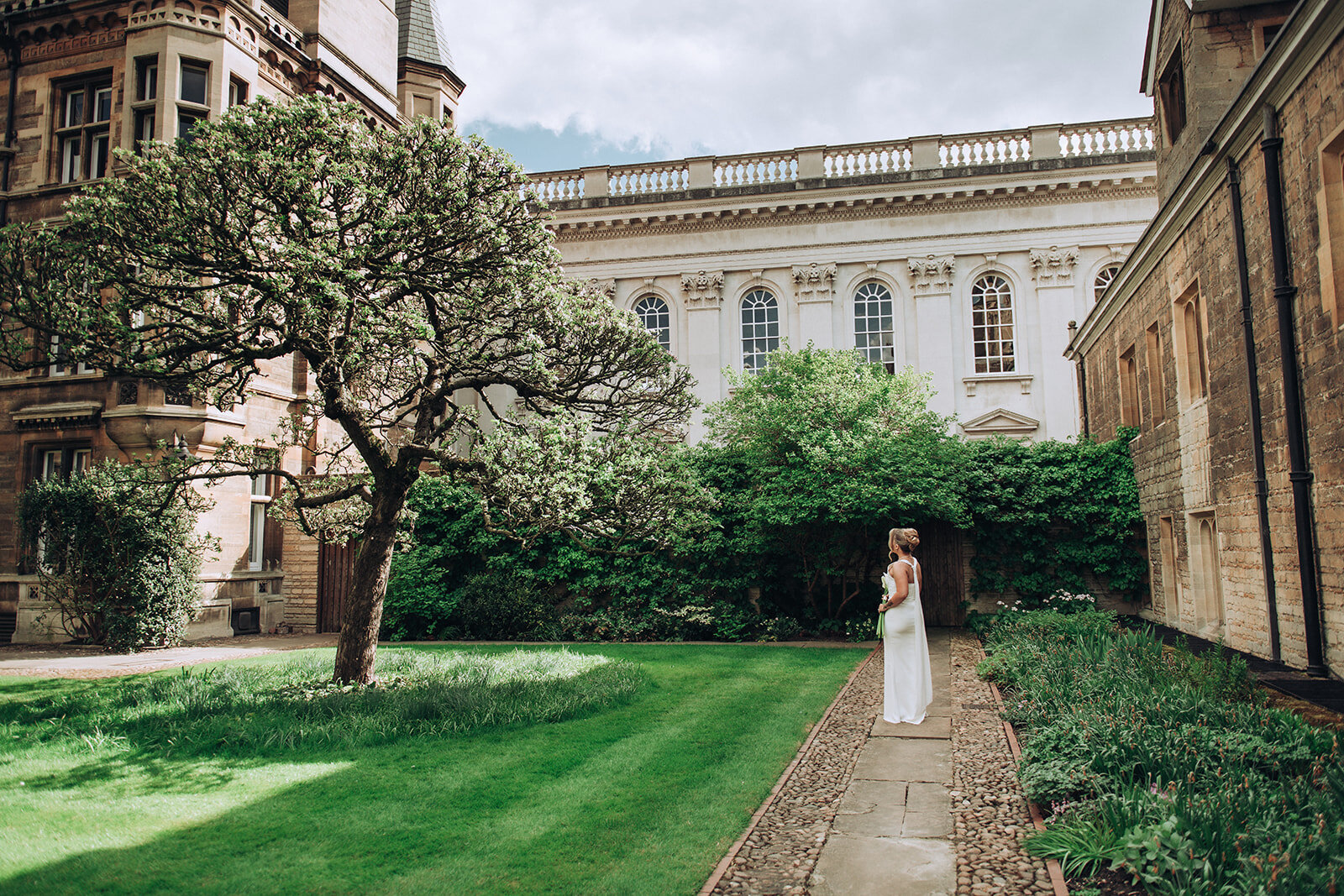 Bride standing amongst trees at her luxury wedding at Gonville & Caius College in Cambridge