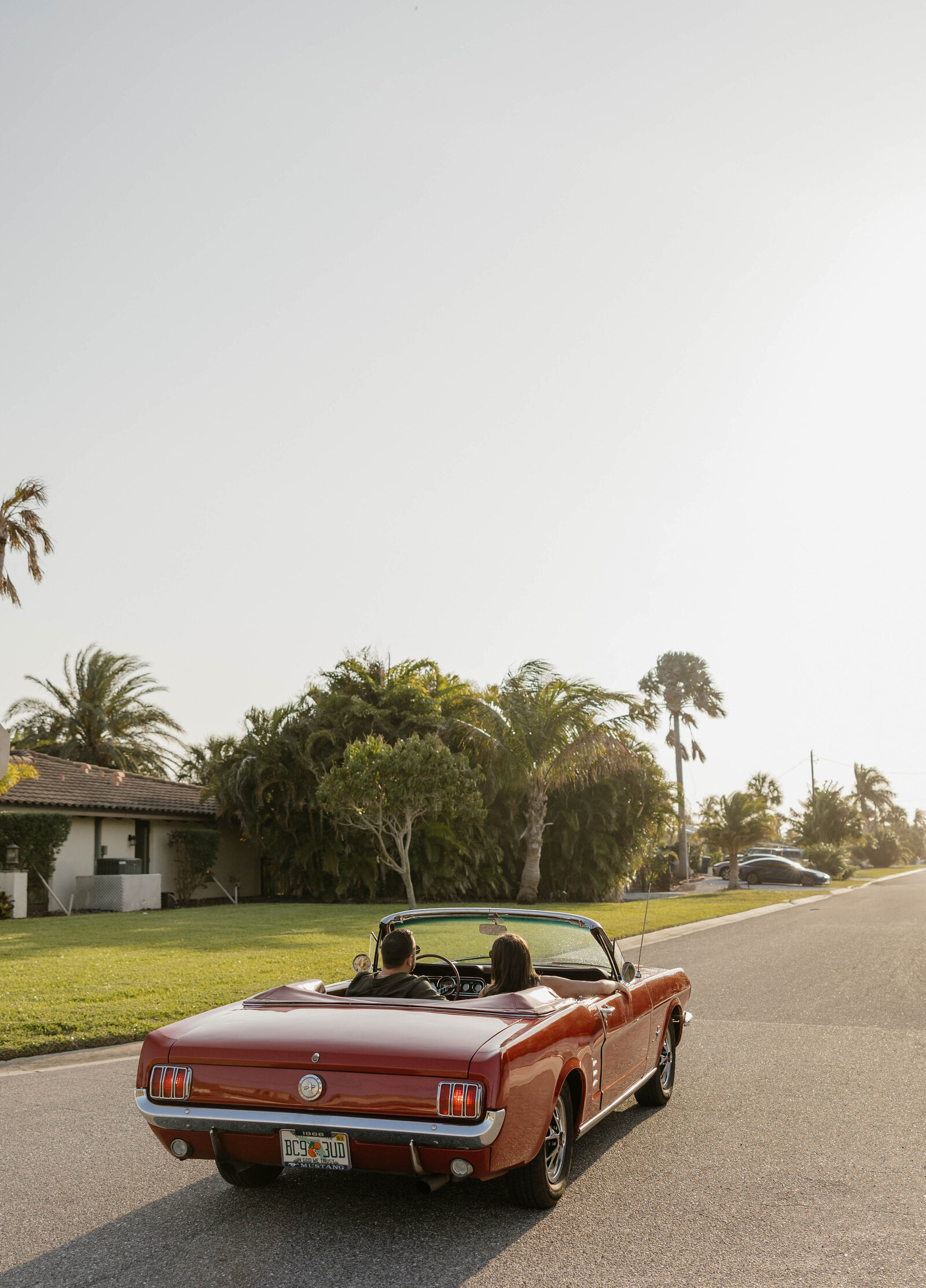 A romantic couple in a vintage car during a photography shoot at sunset.
