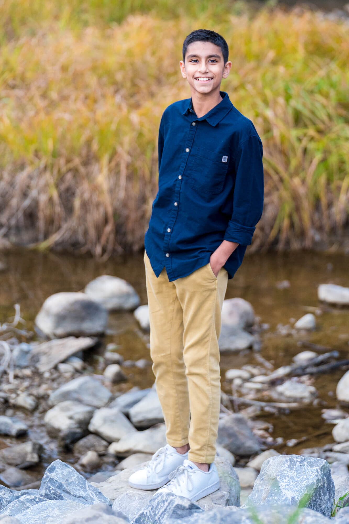 Teenage boy posing on rocks on a shallow river