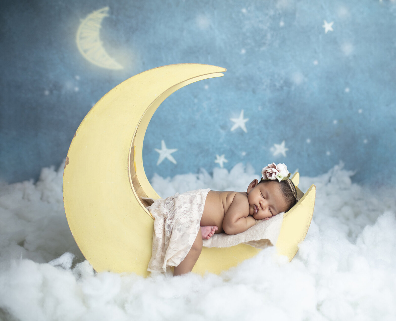Newborn girl posed on the moon in a newborn photographer studio.