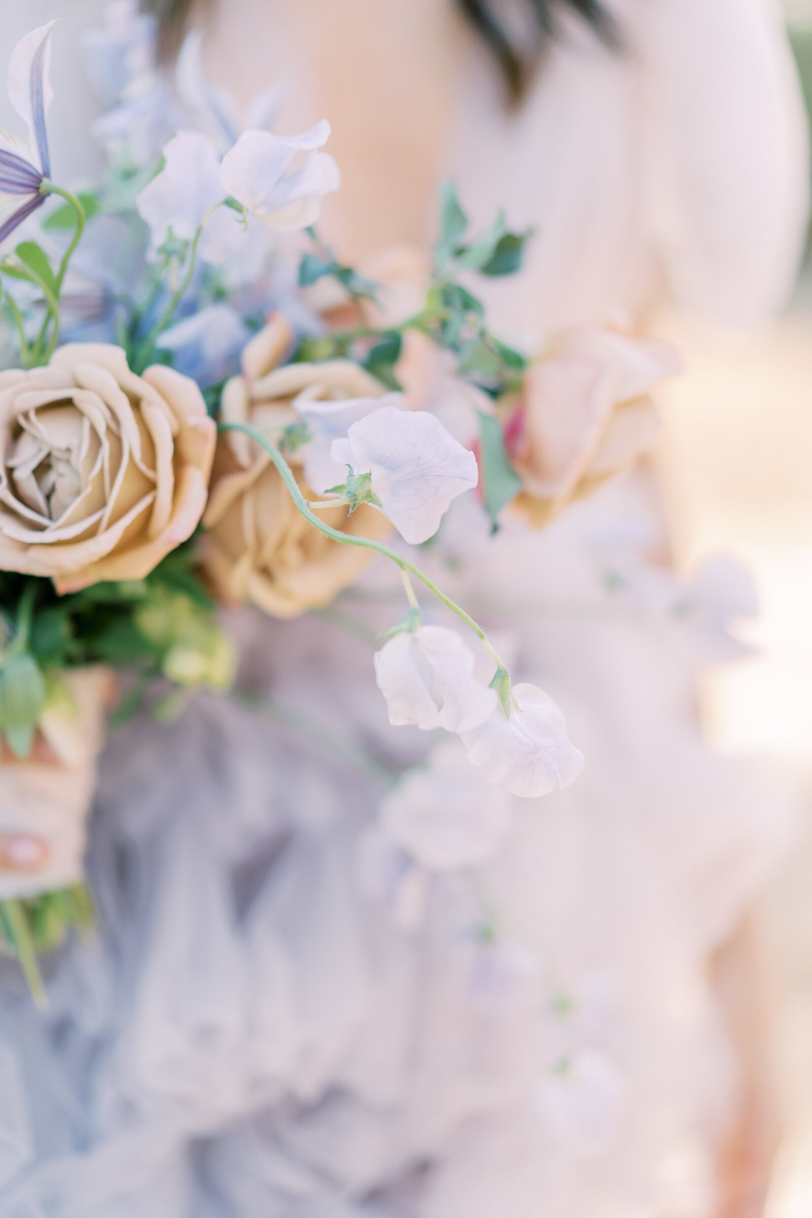 A bride in a lavender gown holding a bouquet of blush and peach flowers.